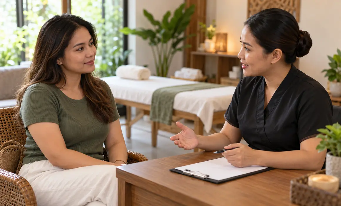 Client discussing a planned massage with a therapist at a consultation desk.